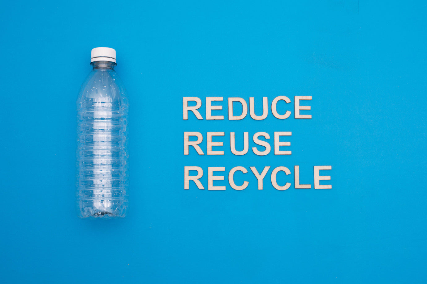 Plastic bottle on a blue background with the eco-friendly message 'Reduce, Reuse, Recycle'—promoting sustainable living and waste reduction.