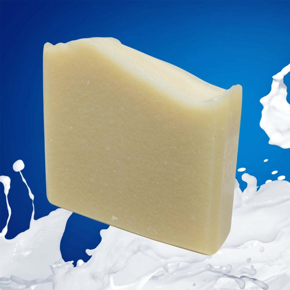 Goat's milk face and body soap bar against a blue background with milk splashes, showcasing natural skincare benefits.